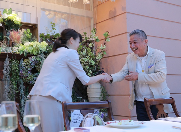 笑顔の会長と握手するパートナー