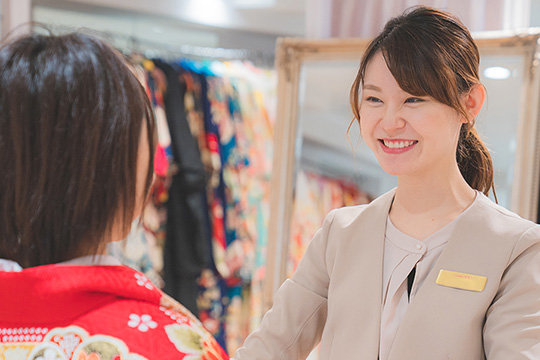 パートナー2人とお客様の3人で写っている写真。脇の2人が「20」の数字をかたどった風船を持ち、お客様がぬいぐるみを持って座っている。